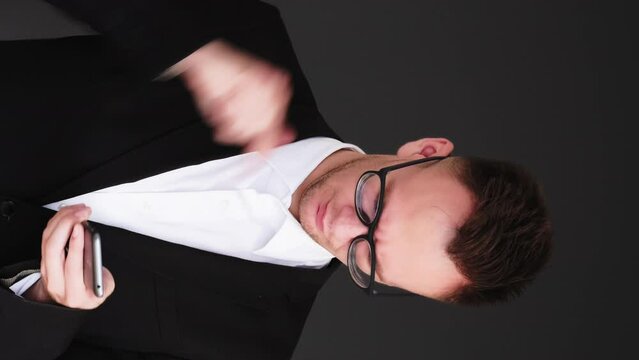 Vertical video. Phone problem. Gadget failure. Technology stress. Annoyed frustrated business man trying to send message isolated on black.
