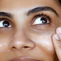 Close-up south asian woman portrait, one hand gently touching the face and applying a cream or...