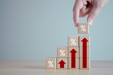 Interest rate finance and mortgage rates. Hand holding wooden block with percentage sign and rise of arrow up, financial growth, interest rate increase, inflation, sale price and tax rise concept.