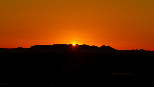 Arizona sunrise with mountains in silhouette and sun rising