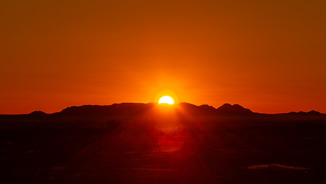 Arizona sunrise with mountains in silhouette and sun rising