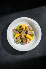 Top view of a duck salad with orange slices and walnuts, a mix of sweet and savory flavors