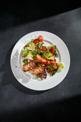 Top view of BBQ ribs with a salad mix on a white plate