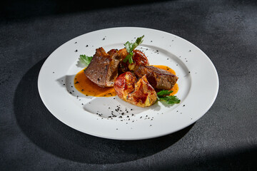 Beef tongue with roasted potatoes on a white plate