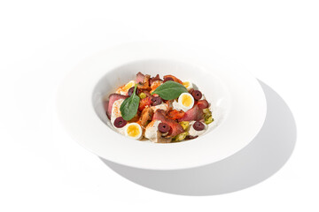 Roast beef salad with quail eggs and vegetables artistically arranged on a white plate