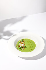 Spinach Cream Soup with Calamari Topping, Artfully Presented on a White Plate with Shadow, Perfect for Gourmet Food Advertising
