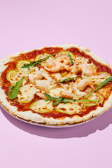 Close-up of gluten-free pizza with shrimp and zucchini on a pink background