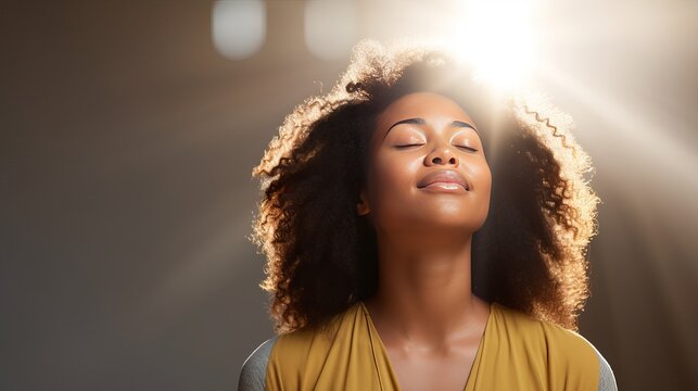 Meditation concept. Beautiful young black woman stands in meditative pose, enjoys peaceful atmosphere, holds hands in praying gesture, isolated over white background, has sense of inner peace