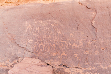 Ancient drawings of animals and life scenes carved into stone on rock wall in the endless sandy red desert of the Wadi Rum near Amman in Jordan