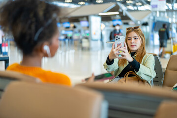 Young woman passengers with suitcase using mobile phone booking hotel during waiting flight at boarding gate in airport terminal. Attractive girl tourist travel by airplane on holiday vacation.