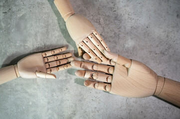 Three wooden mannequin hands isolated on grey marble background. A helping hands concept photo.