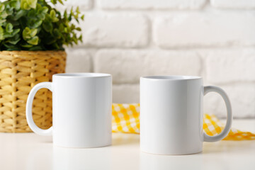 Two mugs on white table against brick wall background