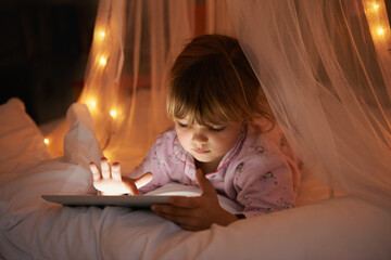 Little girl, bed and tablet at night, browsing and watching with technology for streaming or learning. Child, tech and internet for online games or digital reading with touch and internet in bedroom