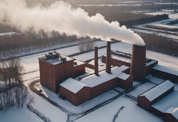 an old red brick boiler room, pipes with a cloud of steam, a winter landscape. A large city boiler house is operating at full capacity