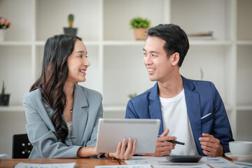 Obraz premium Two business workers smiling happy working sitting on desk at the office.