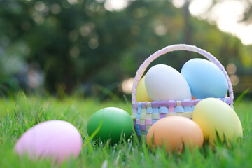 Close up of colorful Easter eggs in a basket on grass in the garden. Happy easter festival celebration. nature background with copy space for text.