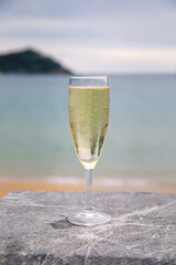 Glass of sparkling Spanish cava wine with a view of the beach and the Concha bay in Donostia or San Sebastian, Spain at sunset