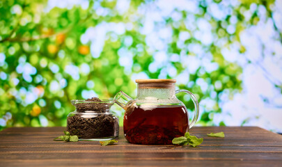 Obraz na płótnie Canvas natural organic herbal tea in glass teapot and jar with dry tea on a wooden table