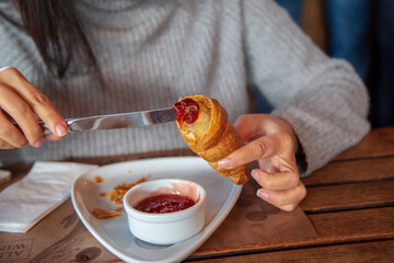 hot croissant, strawberry jam and black tea on a wooden table. 