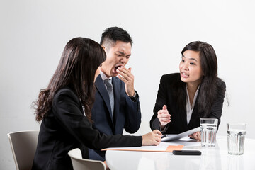Chinese businessman yawning during business meeting