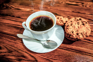 A cup of hot coffee stands on a wooden table
