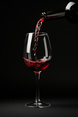 Wine pours into a glass from a bottle on a dark background splashes of wine