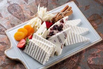 Cheese platter with dry fruits, strawberries, berries on white plate