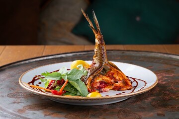 Roasted fish tail served with vegetables on white plate, restaurant menu, dark background