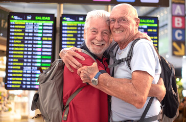 Meeting in the airport terminal. Travel, friends, family hug at the airport, reunion and happiness for trip, escape and joy. Elderly men couple hug each other warmly on arrival or departure journey