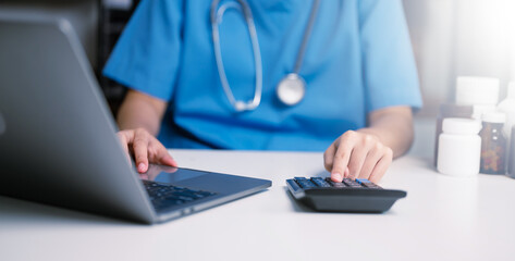 Healthcare costs and fees concept.Hand of smart doctor used a calculator and smartphone, tablet for medical costs at hospital . - obrazy, fototapety, plakaty