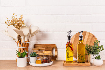 Glass jars with spices and seasonings, stylish oil bottles on the kitchen wooden countertop....