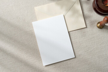 Top view mockup blank card, for greeting, wedding invitation and envelope on earthy neutral colors cloth background. with clipping path
