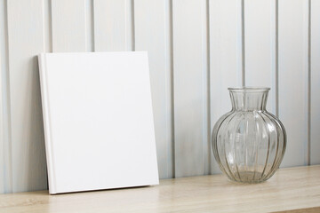 book with an empty white cover and a vase for flowers. mockup album, copy space. the creator of...