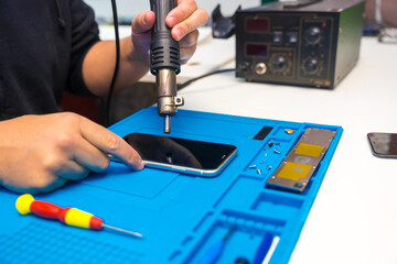 Technician fixing a mobile phone using a soldering iron