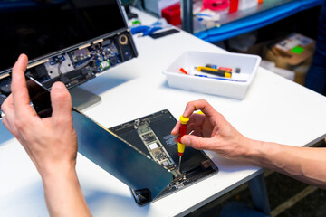 Engineer fixing a digital tablet on a repair workshop
