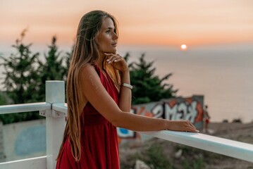 Woman sunset sea red dress, portrait happy beautiful sensual woman in a red long dress posing above the sea on sunset.