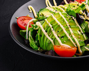 Dietary salad with avocado on a black plate