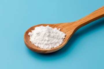 Fototapeta na wymiar white powder on a wooden spoon on blue background