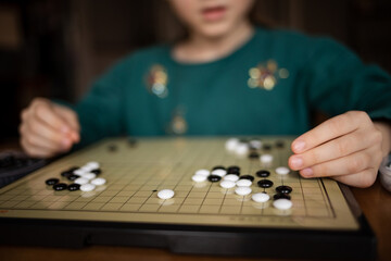 child playing game go. board logic strategy game for developing mind