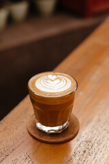 Cappuccino in a glass on a wooden table. Stylish concept for a coffee shop