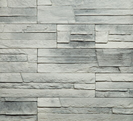 Stone cladding wall made of striped stacked slabs of white and grey rocks. Panels for exterior. Background and texture.