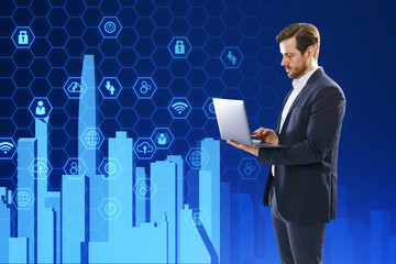 Attractive young businessman using laptop with creative digital city on blue hexagonal background....
