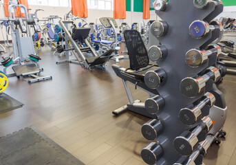 Fototapeta na wymiar Chrome dumbbells rack in fitness club