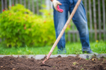 Farmer cultivating land in the garden with hand tools. Soil loosening. Gardening concept....
