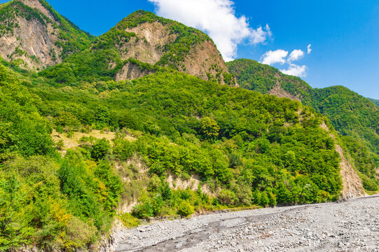 Mountains covered with green forest and blue sky with clouds