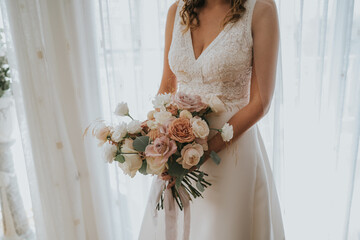 
La joven novia sostiene un hermoso ramo de rosas blancas y rosa pálido. La hermosa novia está al...