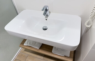 Bathroom Interior with design washbasin on a background of white ceramic tiles. Faucet for water at the white wall background. Luxurious sink white, themed background for interior and design