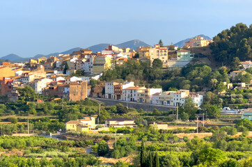 Rural landscape in Segorbe town. Farmhouse at vegetable field. Spain farmland. Cultivation of crops, production of food. House in farm field against backdrop of residential buildings in city