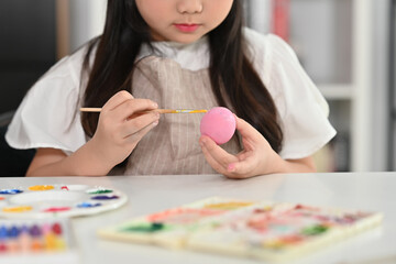 Cropped shot of little girl painting the egg , preparing for Easter at home