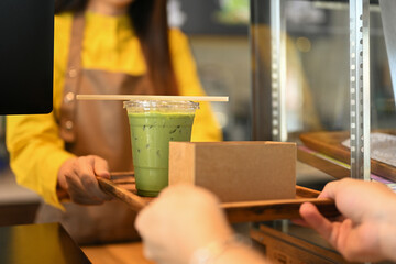 Customer receiving matcha green tea over the counter in modern cafe coffee shop